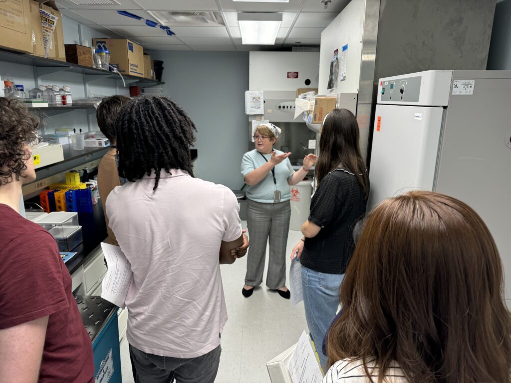 woman pointing to a sign talking to a group of students